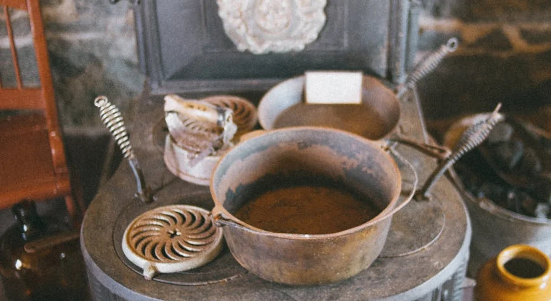 Cast iron pan resting on a vintage stove with oil inside, surrounded by seasoning tools and rags