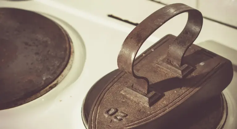 Close-up of a cast iron lid with a looped handle resting on a stovetop.