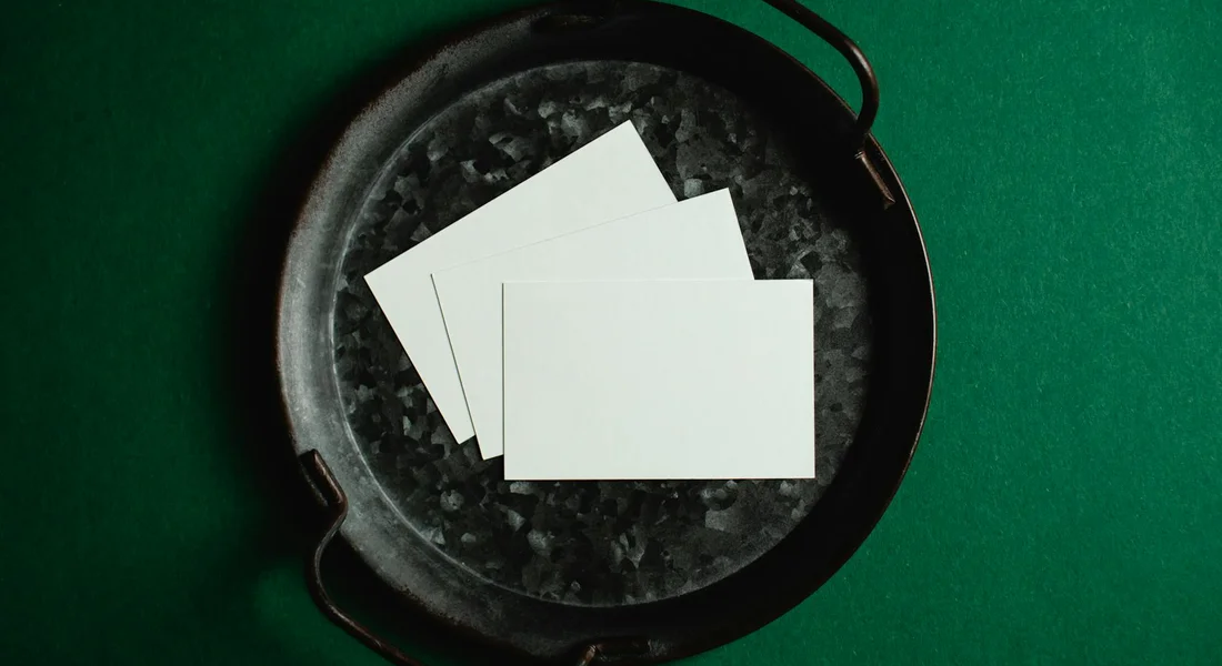 Cast iron skillet on a green surface with several blank white cards resting inside.