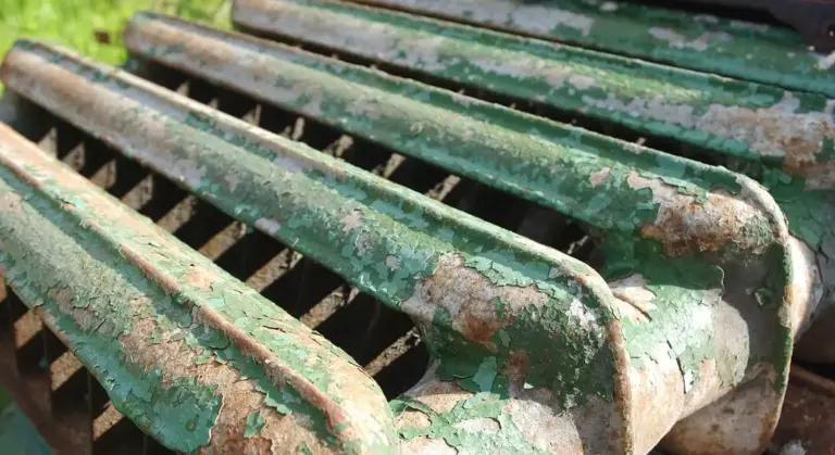 Close-up of weathered cast iron scrap with green peeling paint and rust.