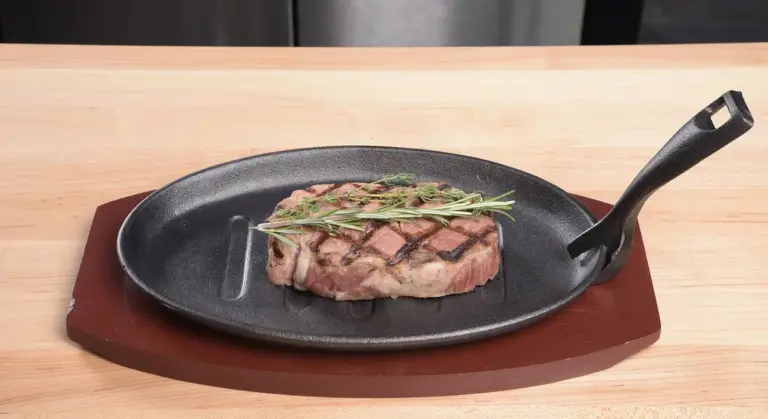 Steak seared in a cast-iron skillet with a sprig of rosemary on top.