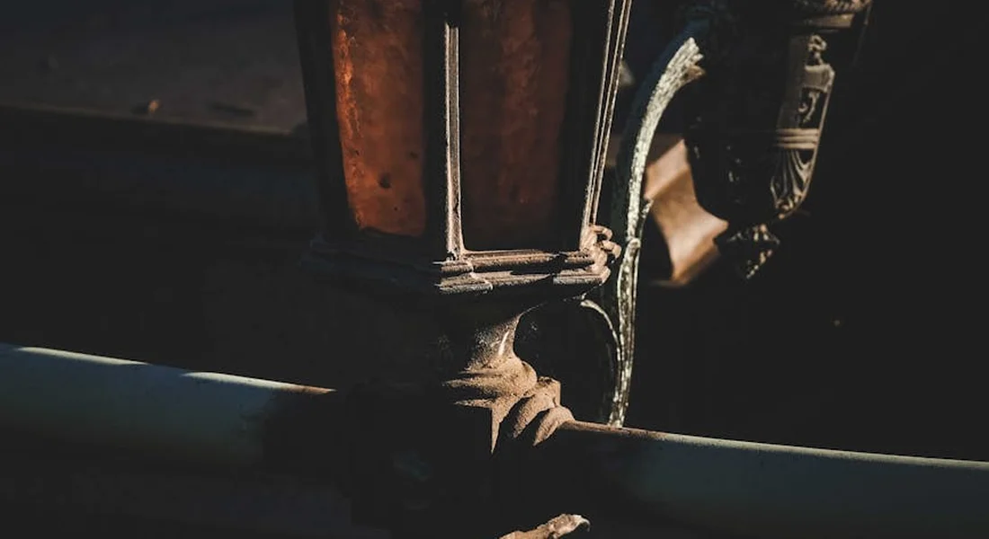 Close-up of weathered cast-iron hardware with a dark workshop background, illustrating the need for paint removal.