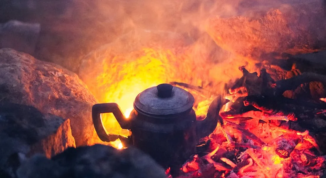 Cast iron teapot heating on hot embers