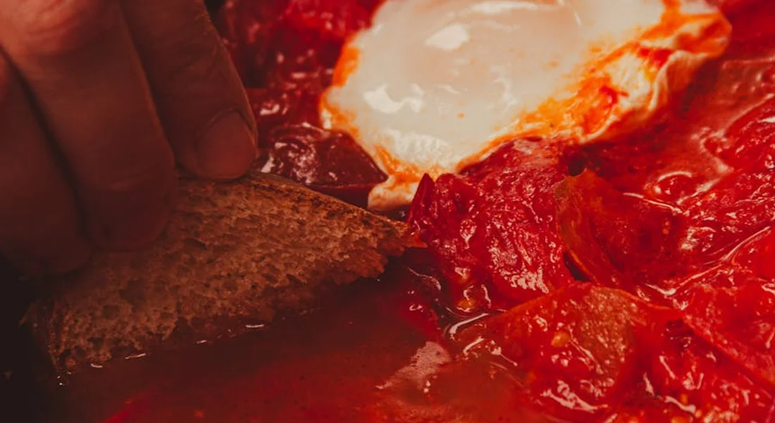 Close-up of a spatula stirring a pan filled with red tomato sauce during home cooking