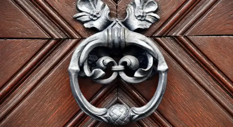 Close-up of a decorative metal door knocker mounted on a wooden door