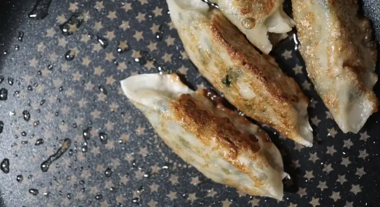 Gyoza dumplings browning in a star-pattern cast iron skillet