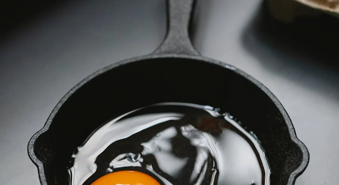 Sunny-side-up egg cooking in a seasoned cast-iron skillet.