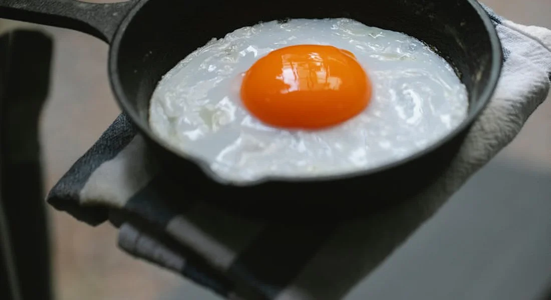 A fried egg in a seasoned cast iron skillet resting on a folded cloth.