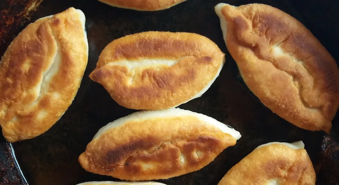 Golden-brown fried dough pieces resting in a dark cast-iron pan.