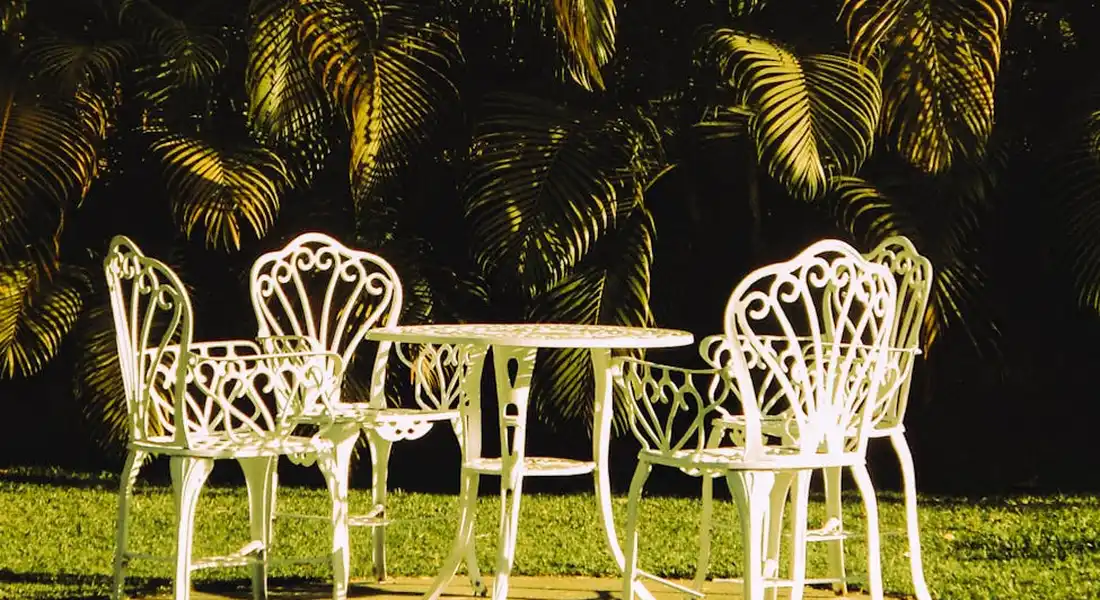 White cast-iron patio table and chairs in a sunlit garden