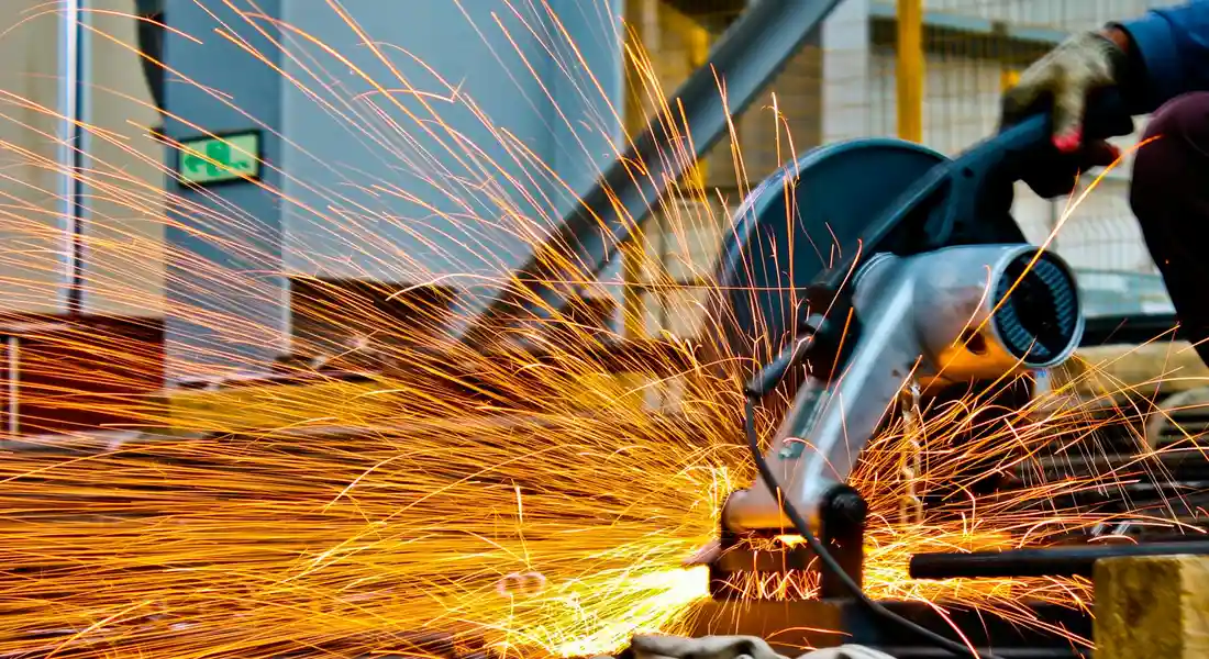Close-up of industrial metalworking: sparks fly as a grinding tool shapes iron in a factory