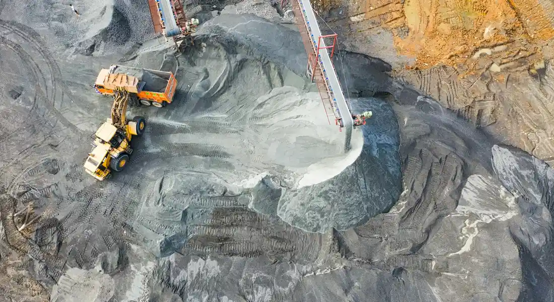 Aerial view of heavy mining equipment excavating rock to extract raw materials for steel production.