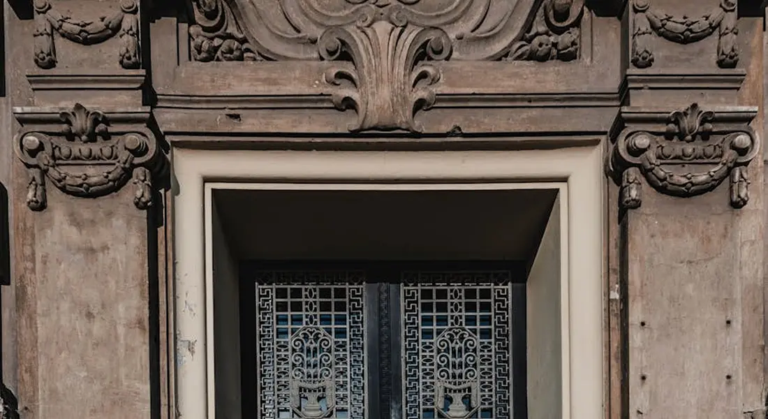 Close-up of an ornate doorway with a decorative wrought-iron gate set in a carved stone frame