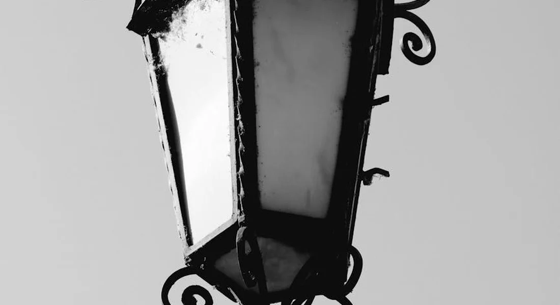 Close-up of a decorative black iron lantern with scrollwork, shown in grayscale