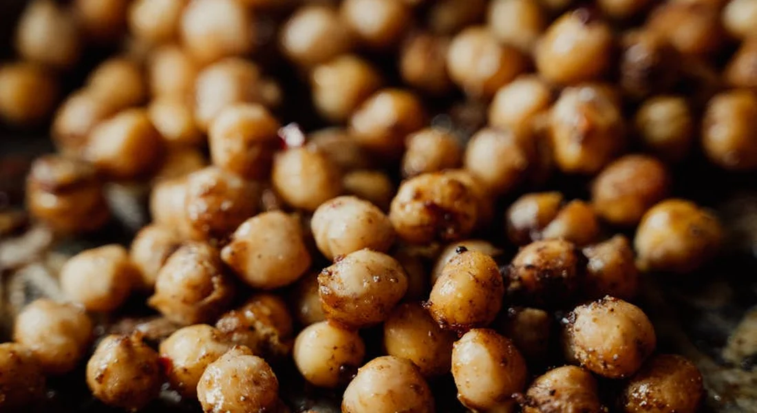 Close-up of roasted chickpeas scattered on a dark surface