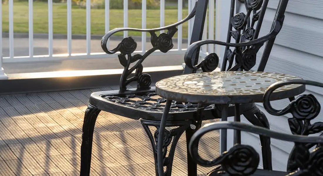 Wrought-iron outdoor furniture with rust spots on a porch.
