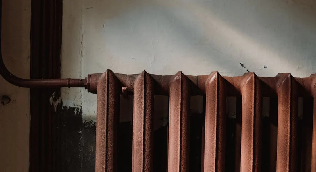 Close-up of a rusty cast-iron radiator with flaking paint