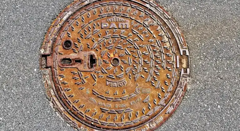 Rusty cast-iron manhole cover on asphalt