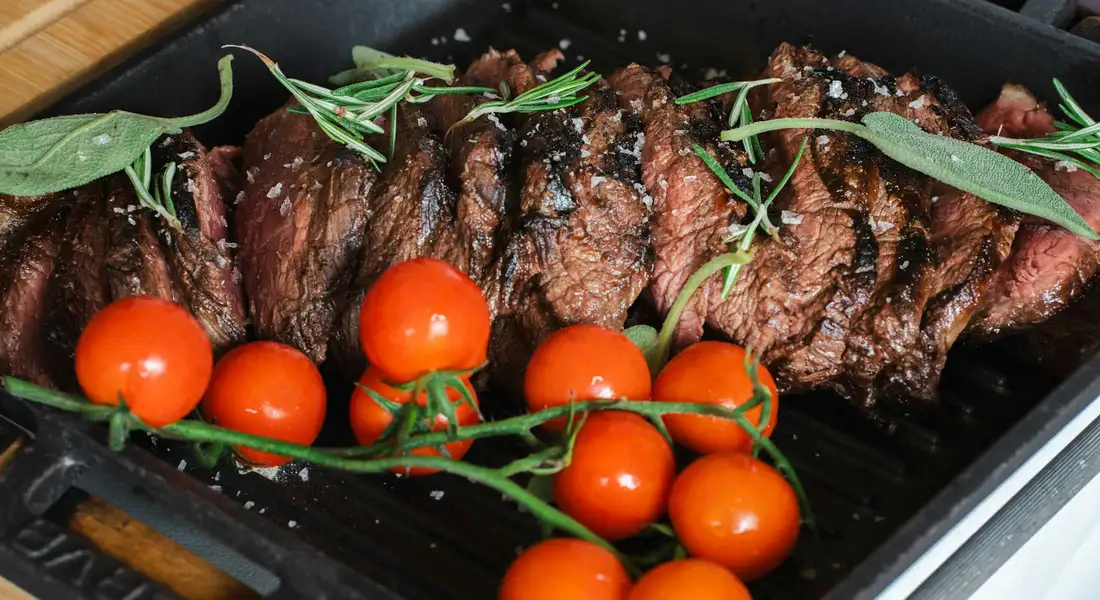 Beef slices on a pan with cherry tomatoes and fresh herbs